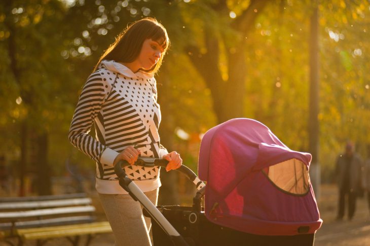 Kvinde går med sin baby i barnevogn